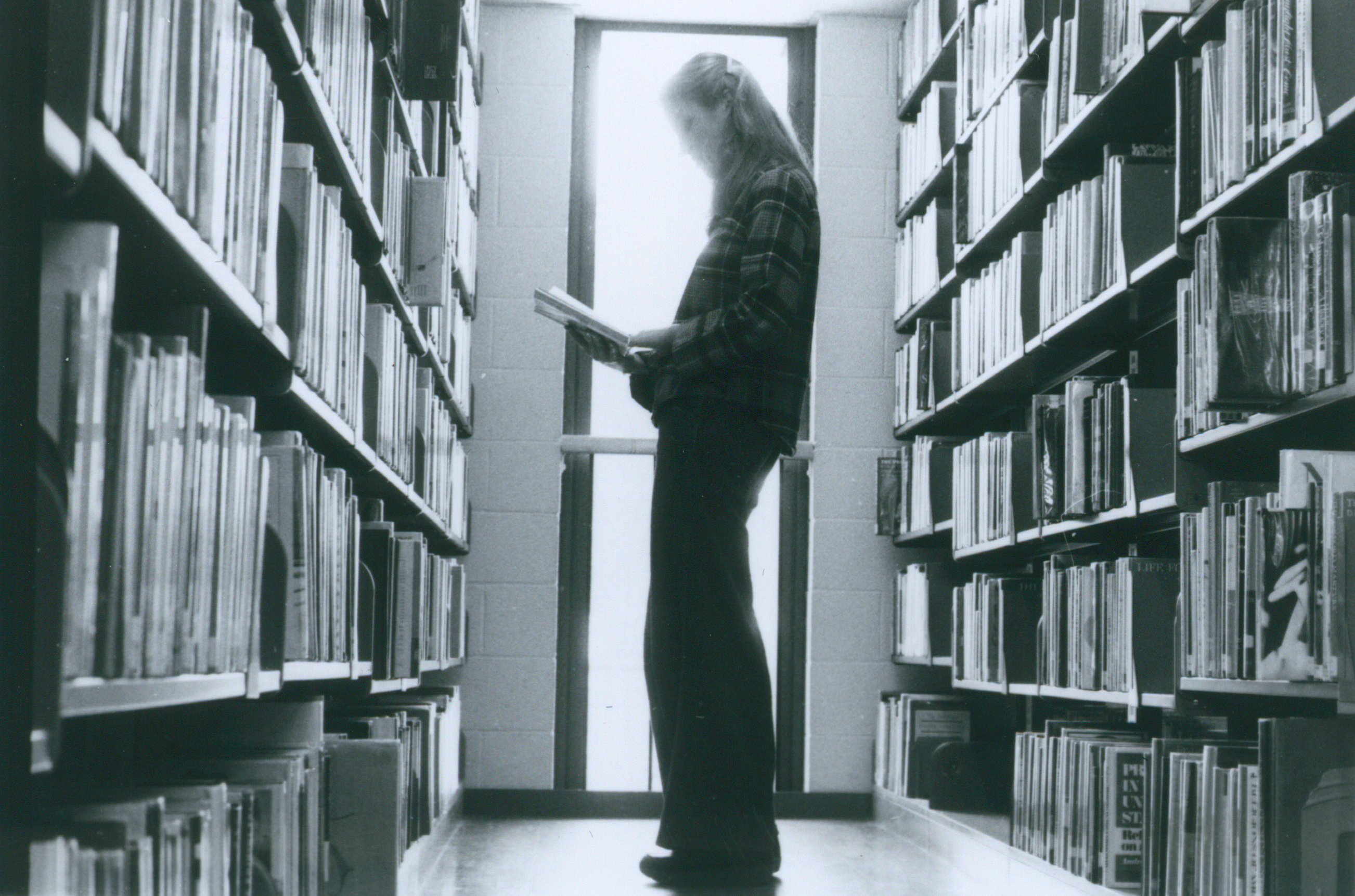 visitor reading in the bookstacks in 1978