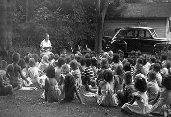 Elinor Haff reads to youngsters on back lawn, 1949