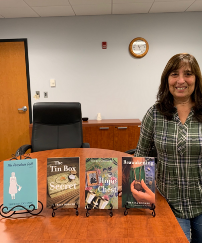 Picture of local author Theresa Dodaro, with three of her novels.