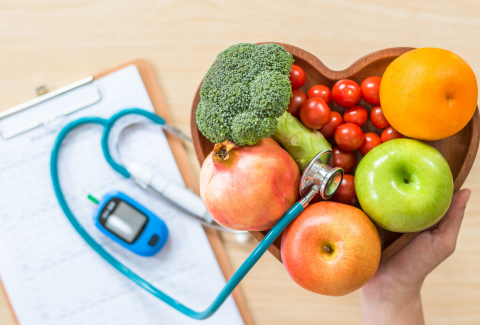 picture of bowl of fruit with a stethoscope and a glucometer.