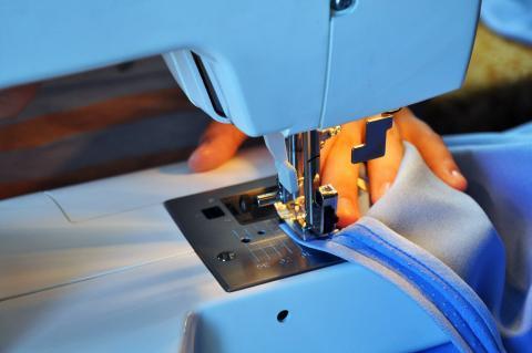 Close up of a sewing machine with a piece of fabric underneath the needle.